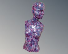 A feminine mannequin head and torso decorated with peacock feathers.