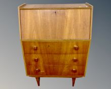 A mid-20th century teak bureau on raised legs fitted with three drawers beneath.