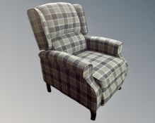 A reclining fireside chair upholstered in a checkered fabric.
