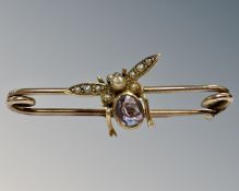 An antique yellow gold bar brooch mounted with seed pearl and amethyst winged insect, 2.5g gross.