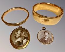 Two antique gold plated bangles together with two pendants.