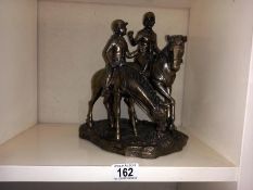 A silver resin horse and rider figure group