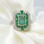 An Art Deco-inspired ornate platinum ring set with emeralds and diamonds
