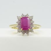 A 9ct yellow gold step-cut ruby ring surrounded by a halo of diamonds