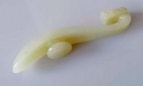 A Chinese 19th century celadon jade belt buckle hook with carved dragon head terminal and plain curv