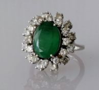 An emerald and diamond cluster ring, the oval emerald 12mm x 9mm, surrounded by twenty four round