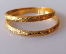 A pair of gold bangles with etched floral decoration, stamped and testing for 22ct, internal