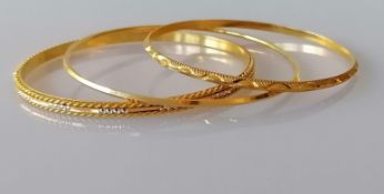 Three gold bangles, two with etched decoration, 60mm, 63mm x 2 diameter, unmarked but testing for