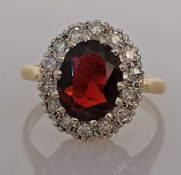 An oval garnet cluster gold ring surrounded by fourteen round-cut diamonds, each 0.02 carats