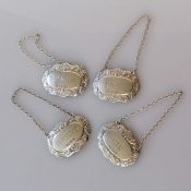 A set of four silver bottle labels with shell scroll decoration, Sherry, Port, Brandy & Gin