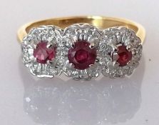 A yellow gold three-stone ruby ring, the central stone approximately 0.20 carats