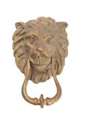 A brass lions head door knocker with open mouth holding the looped knocker, 22cm high.