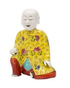 A Chinese famille rose figural joss stick holder of a seated laughing boy,