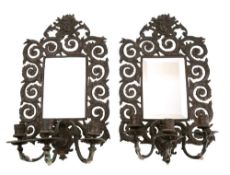 A pair of bronzed metal and mirrored girandoles of arched outline,