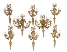 A pair of gilt brass four branch wall appliques and six matching twin-branch appligues with ribbon