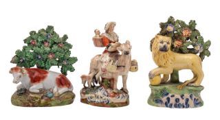 A Staffordshire pottery bocage figure of a lion; a similar figure of a cow;