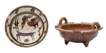 Two Persian bowls, one with lug handles and notched rim set on three peg feet under brown glazes,