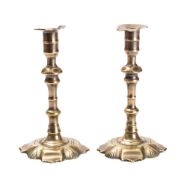 A pair of early 18th century brass candlesticks with urn-shaped sconces, on knopped stems,