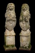 A pair of stone composition garden models of heraldic lions,