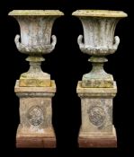 A pair of Victorian stoneware twin handled garden urns on plinths,