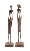 A pair of African bronze figures of elongated form, raised on square plinth bases, 29cm high.