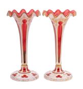 A pair of Bohemian ruby and white overlay glass lustre stands with frilled rims,