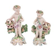 Two Chelsea-Derby figures of putti each holding a basket of flowers and on rococo scrollwork mound