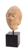 An Indian carved sandstone head of a moustachioed man with shaved head, furrowed forehead,