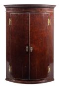 A George III mahogany bow fronted hanging corner cabinet,