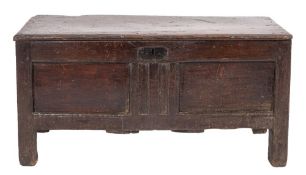 An oak coffer, second half 17th century; the hinged cover above a chenneled and twin panel front,