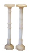 A pair of alabaster pedestals with square capitals with canted corners on a ring turned column and
