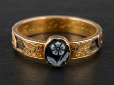 A late Victorian, gold, mourning ring, set with a carved sardonyx depicting a forget-me-knot,