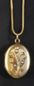 An oval locket pendant with seed pearl decoration in floral motif,