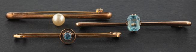 Three bar brooches, including a blue topaz brooch, stamped '9CT'; an imitation pearl brooch,