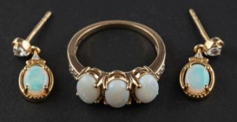 An oval cabochon-cut opal, three-stone ring, with white paste to shoulders, stamped 10K,