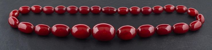 A graduated red amber bead necklace, length of beads ca. 1.3-2.8cm, total length ca.