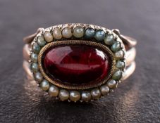 A Georgian mourning ring, the foiled back garnet with seed pearl surround,