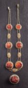 A filigree necklace of graduated carnelain plaques carved with floral motifs, stamped 'CHINA',