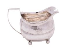 A Georgian silver cream jug, maker's mark worn R?, crested, of barge-shaped outline,