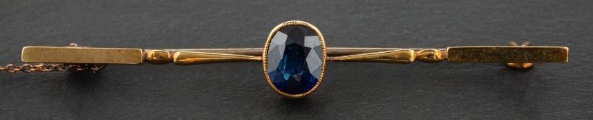 An oval, mixed-cut synthetic sapphire bar brooch, stamped '15CT', length ca. 5.