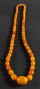 A graduated, amber bead necklace, the amber of varying hue from yellow to brownish orange,