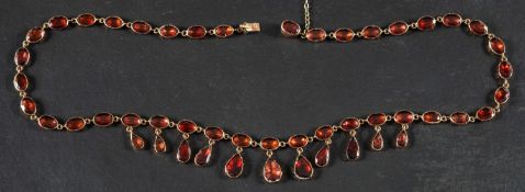 A late Georgian, 9ct gold, flat-cut, foiled-back, collet-set, garnet fringe necklace,