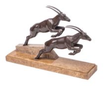 An Art Deco bronze patinated metal group of two leaping gazelles mounted on a polished marble base,