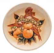 A John Moorcroft pottery plate, tube lined in the Finches pattern on a peach ground,
