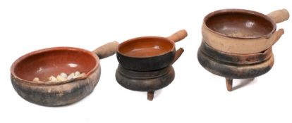 Five graduated terracotta and slip glazed single handled cooking pots with single lipped bowls.