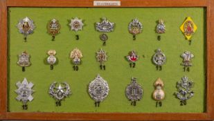 A framed group of twenty British Army Staybright cap badges, including The Queen's Regiment,