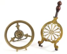 A 19th Century brass mounted iron trivet with pierced flowerhead design, having turned wood handle,