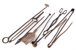 A collection of wrought iron fire implements, including tongs, pokers, rake and shovel.