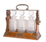 A Victorian oak and silvered metal mounted three-decanter tantalus, late 19th century,