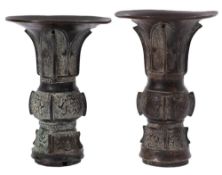 A matched pair of Chinese bronze vases, Gu with flared necks,